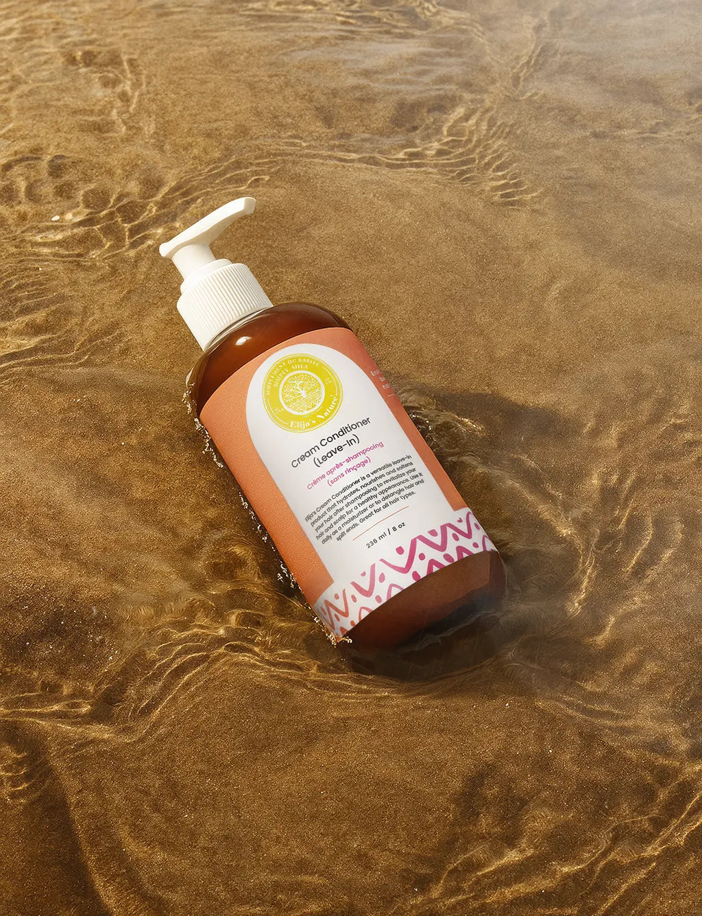 Cream Conditioner Leave-In - #size_8oz - Elija’s Nature Cream Leave-In Conditioner bottle placed diagonally on rippled sand in natural sunlight