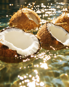 #scent_Olive Coconut - Halved coconuts floating in clear water, reflecting sunlight, suggesting tropical freshness and natural ingredients