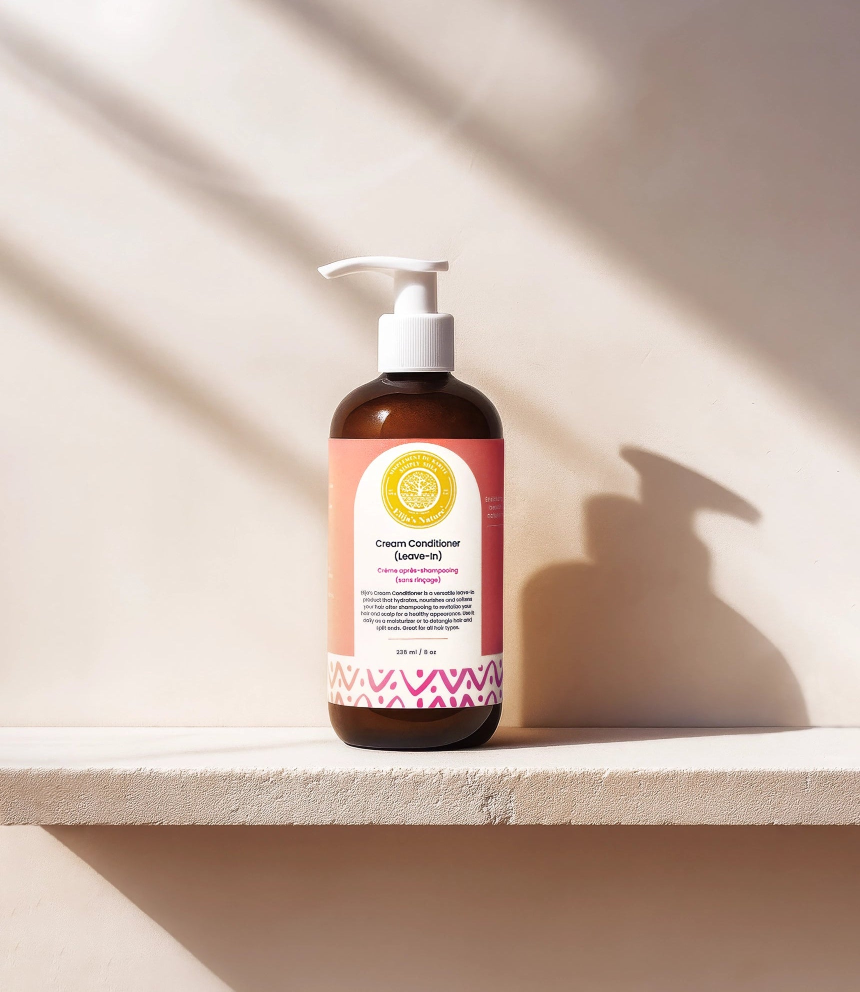 Cream Conditioner Leave-In - #size_8oz - Bottle of Elija’s Nature Cream Leave-In Conditioner standing on a white ledge, casting a strong shadow against a beige wall