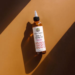 Hair N' Scalp Oil - #size_8oz - Elija’s Nature Hair n’ Scalp Oil bottle lying diagonally on a warm brown surface with strong directional light and shadow
