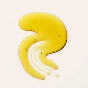 Hair n' Scalp Oil swatch with visible herbs air bubbles, curved into an organic shape on a beige background
