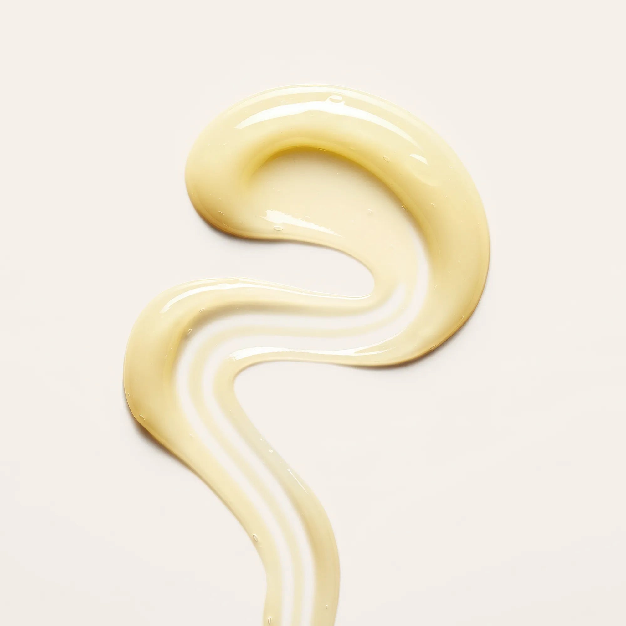 Leave-In Cream Conditioner swatch with a smooth, curled texture on a beige background