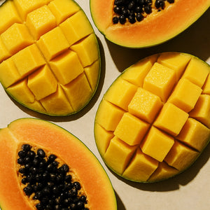 #scent_Mango Papaya - Halved papayas and mangoes, with papayas showing black seeds and mangoes cubed, arranged on a light background