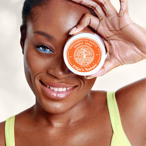 Golden Body Butter - #scent_Mango Papaya #size_8oz – A smiling woman in a lime green top holds a small jar of Mango Papaya body butter over one eye in a fresh, engaging way